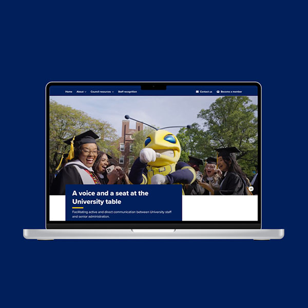 Laptop showing a website with graduates and a mascot on the screen.